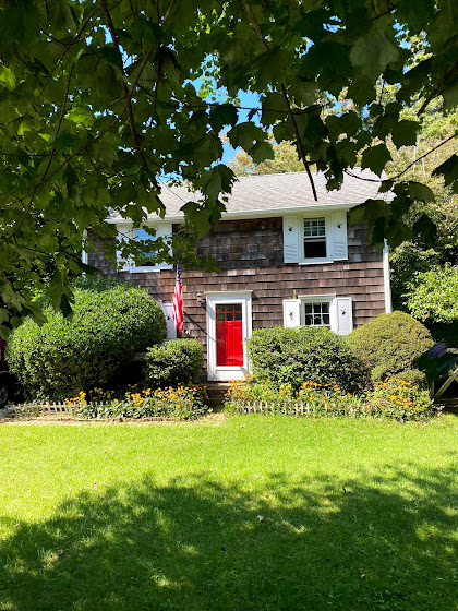 Weekend in The Hamptons: Class shingle style house with American flag and red door in East Hampton, New York