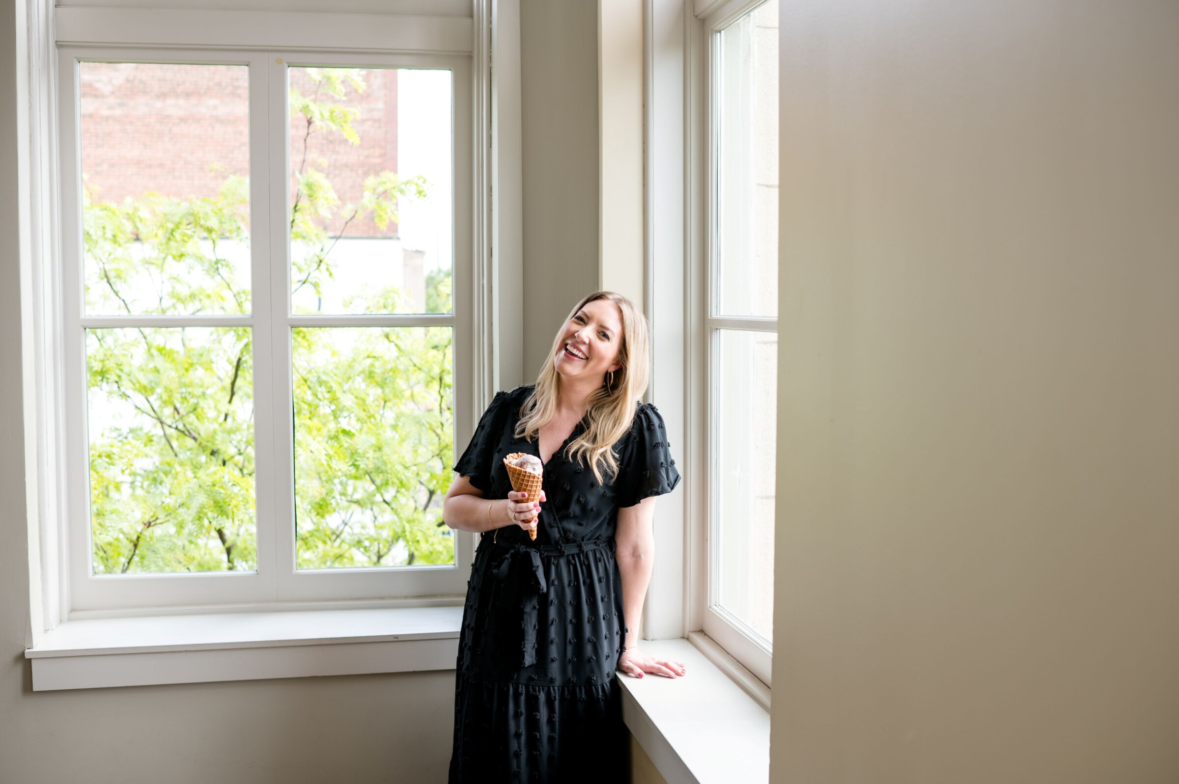 Darcy Warden by a window holding an ice cream cone during a branding session